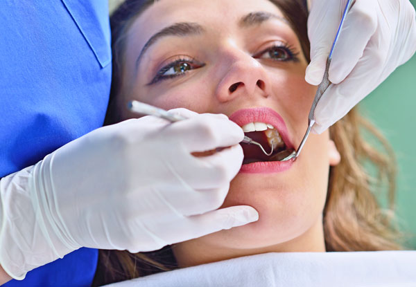 young woman getting teeth inspected by dental assistant